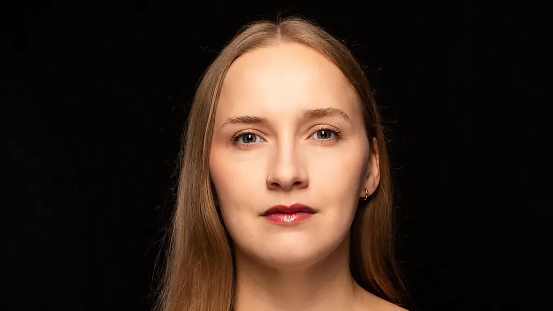 Leonie Plaar trägt ein schwarzes Oberteil und steht vor einem schwarzen Hintergrund. Sie schaut direkt in die Kamera. Leonie Plaar trägt ein schwarzes Oberteil und steht vor einem schwarzen Hintergrund. Sie schaut direkt in die Kamera.
