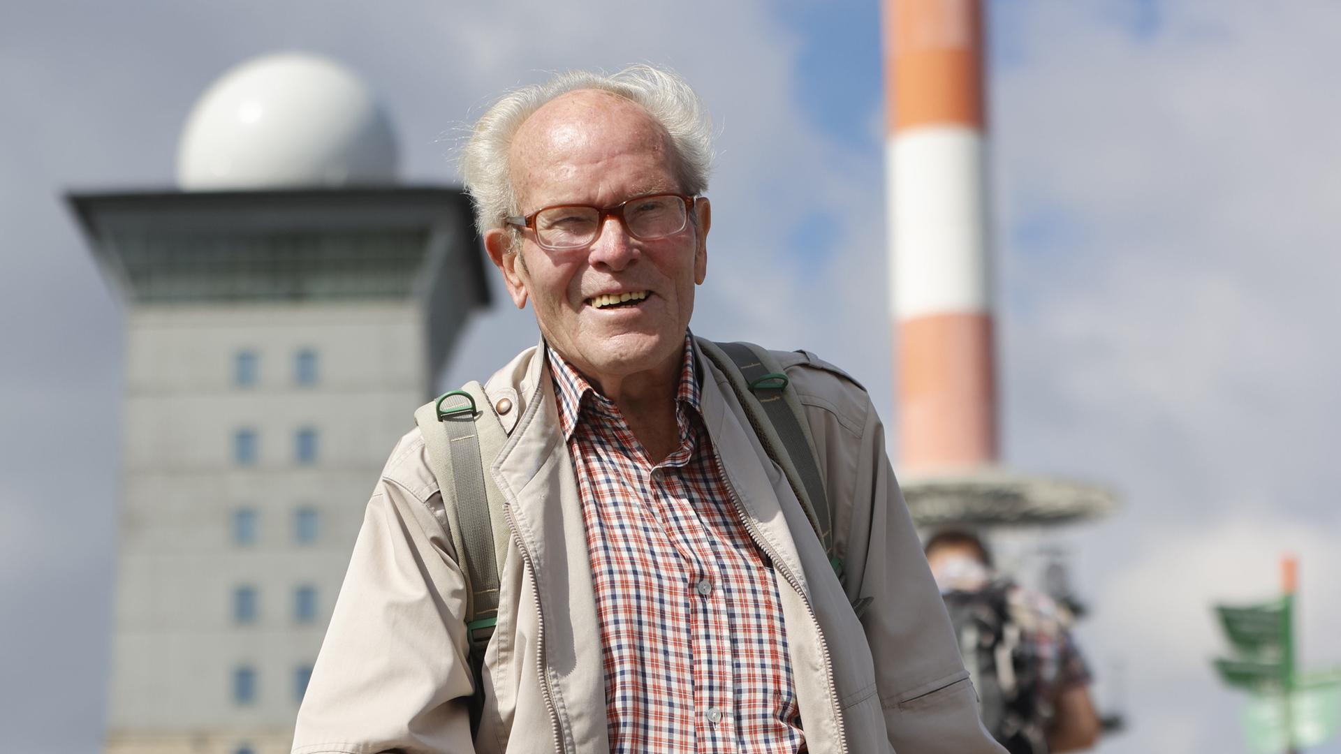 Extremwanderer und Wanderführer Benno Schmidt, Brocken-Benno genannt, steht mit Rucksack und Wanderstock vor der Funkstation auf dem Brocken.