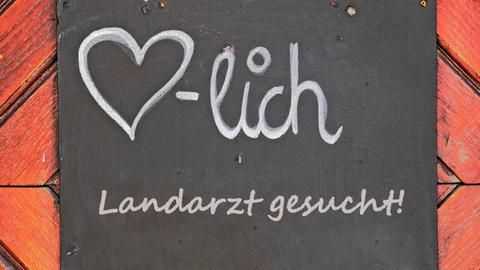 Auf einem Schild steht: Landarzt gesucht!