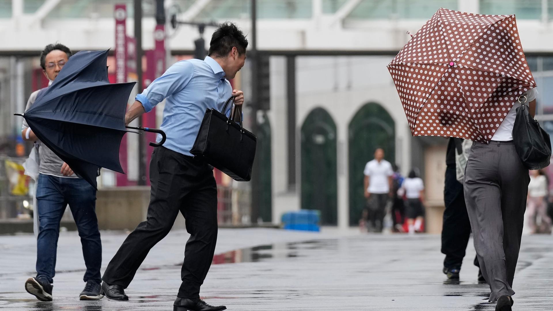 Tokio: Ein Mann versucht, im Sturm seinen Schirm festzuhalten. Tokio: Ein Mann versucht, im Sturm seinen Schirm festzuhalten.