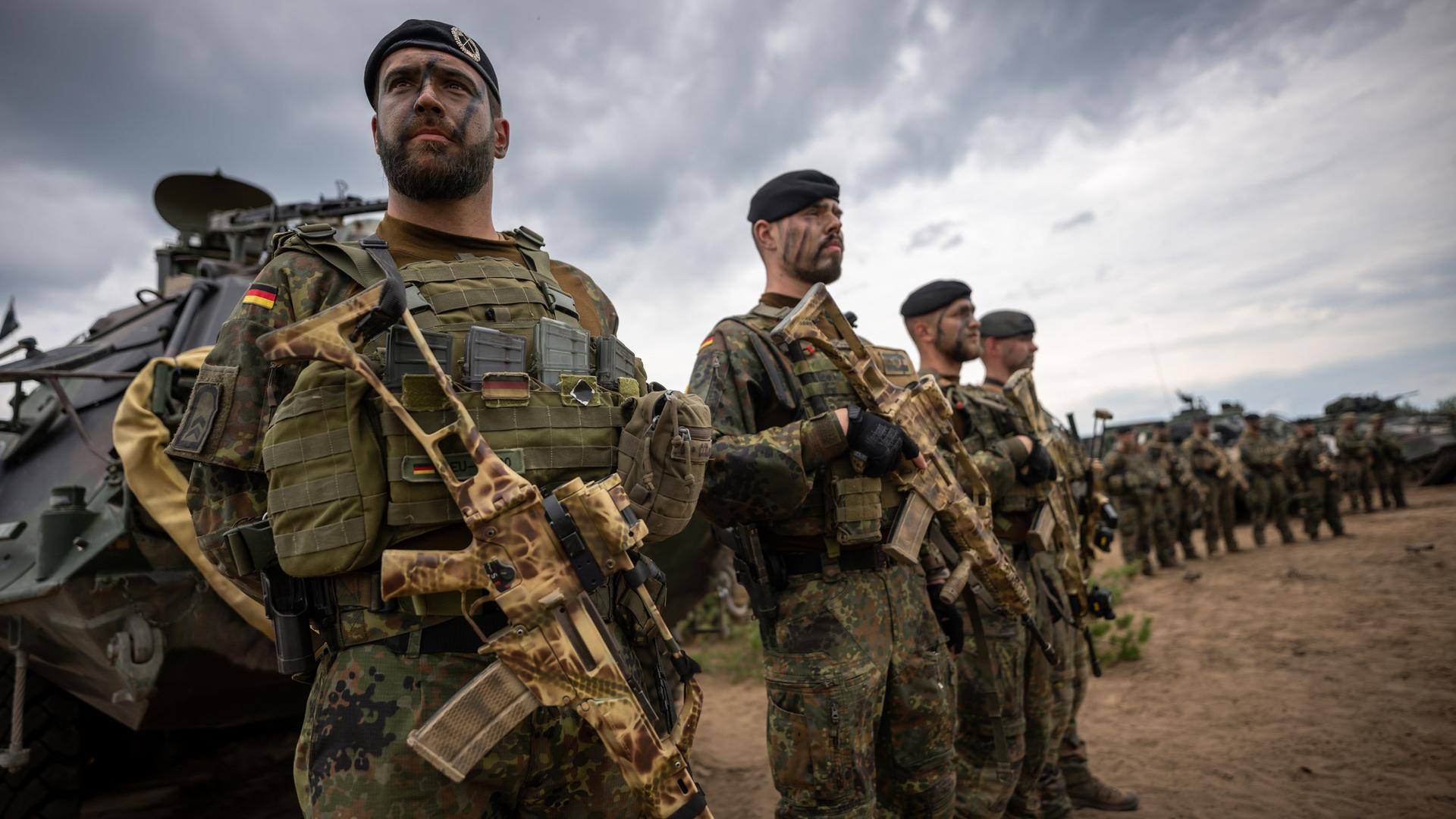 Soldaten der Bundeswehr in Uniform und mit Waffen in der Hand stehen zum Appell.