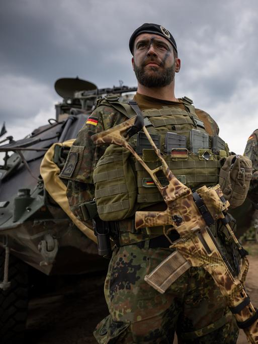 Soldaten der Bundeswehr in Uniform und mit Waffen in der Hand stehen beim Besuch von Kanzler Scholz im Camp Adrian Rohn. Bundeskanzler Scholz (SPD) hat Litauen zusätzliche militärische Unterstützung zugesagt.