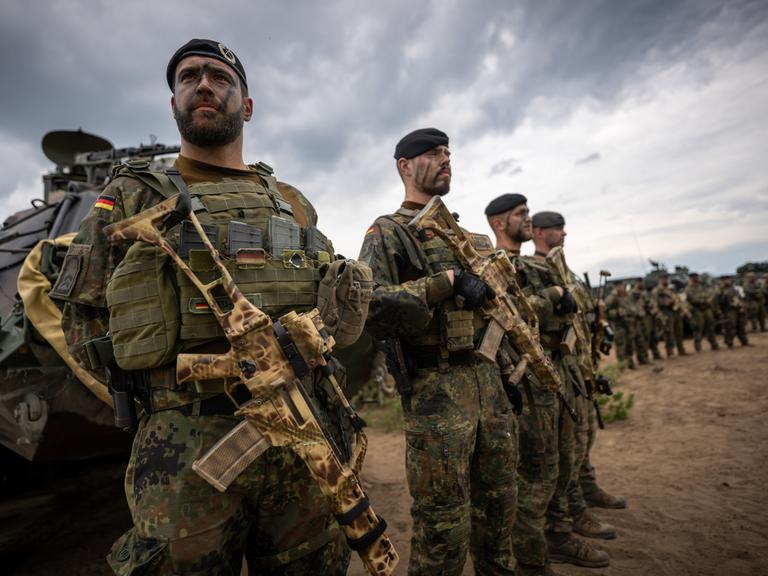 Soldaten der Bundeswehr in Uniform und mit Waffen in der Hand stehen beim Besuch von Kanzler Scholz im Camp Adrian Rohn. Bundeskanzler Scholz (SPD) hat Litauen zusätzliche militärische Unterstützung zugesagt.