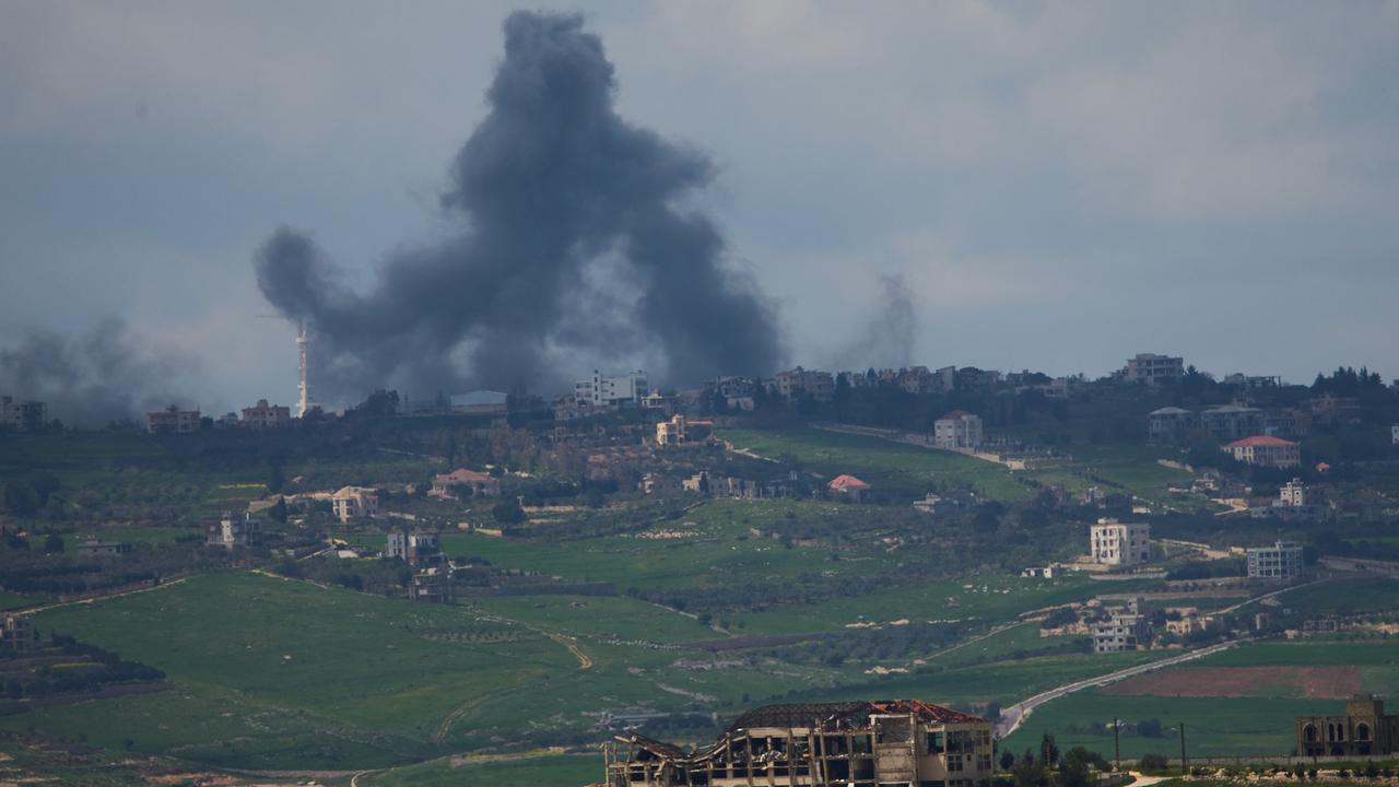 Nach einem Raketenangriff steigt Rauch am Horizont einer ländlichen Gegend auf, im Vordergrund ist ein zerstörtes Haus zu sehen.