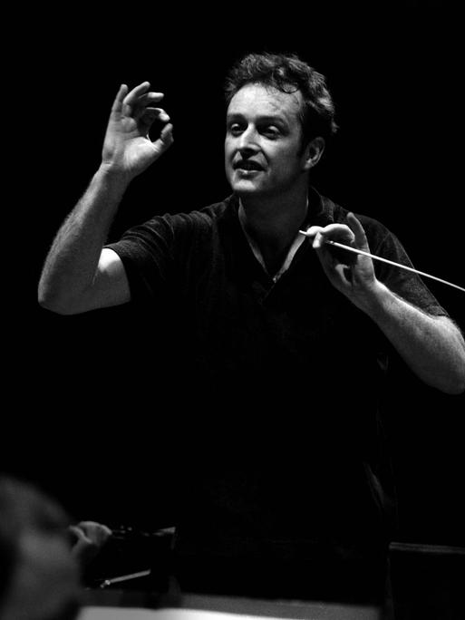 Der Dirigent Carlos Kleiber steht vor dem Orchester und dirigiert.