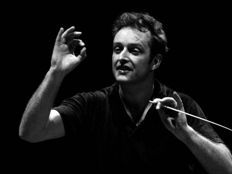 Der Dirigent Carlos Kleiber steht vor dem Orchester und dirigiert.