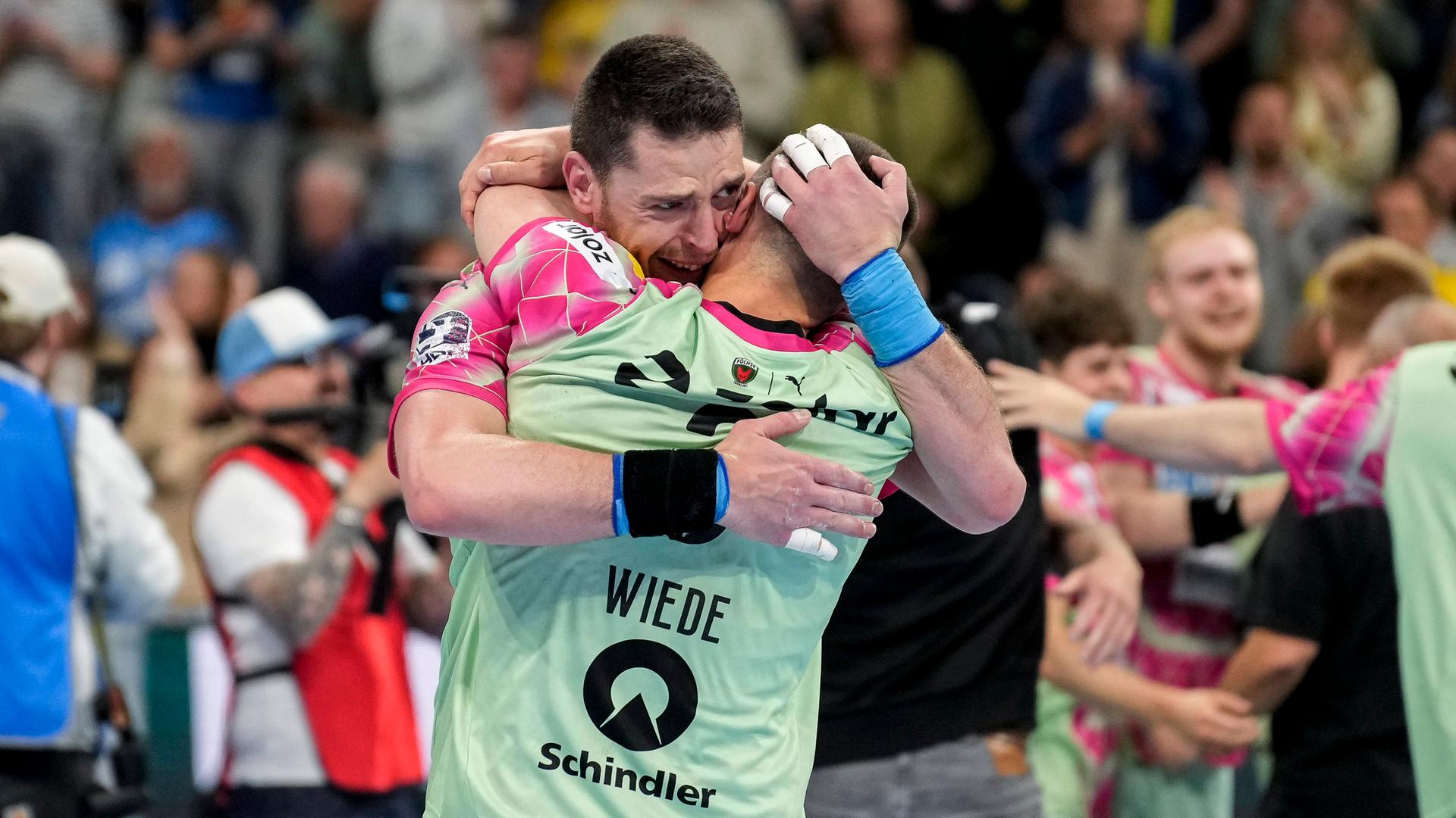 Zwei Berliner Handball-Spieler umarmen sich.