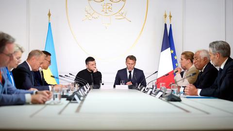 Frankreichs Präsident Macron und der ukrainische Präsident Selenskyj sitzen an einem Tisch umringt von weiteren Staats- und Regierungschefs, die sich als "Koalition der Willigen" zur Unterstützung der Ukraine verstehen. 