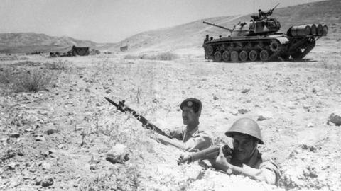 Zwei jordanische Soldaten beziehen bewaffnet Stellung an der Grenze zu Israel. Im Hintergrund ist ein Panzer zu sehen.