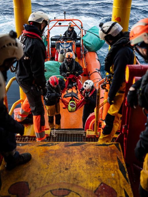 Die Besatzung eines Bootes der Seenotrettung bei einer Übung. Eine Puppe wird aus einem Rettungsboot auf das Hauptboot umgesetzt.