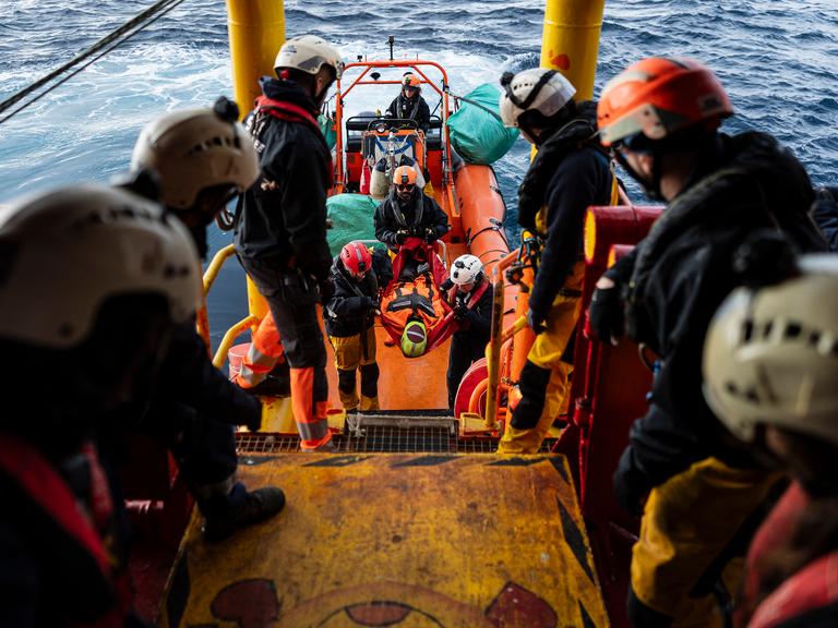 Die Besatzung eines Bootes der Seenotrettung bei einer Übung. Eine Puppe wird aus einem Rettungsboot auf das Hauptboot umgesetzt.