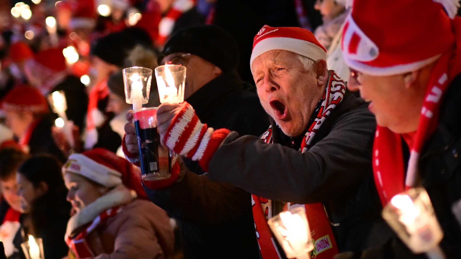 Weihnachtssingen im Stadion von Union Berlin. Ein Mann mit einer Nikolausmütze singt lauthals mit. 
