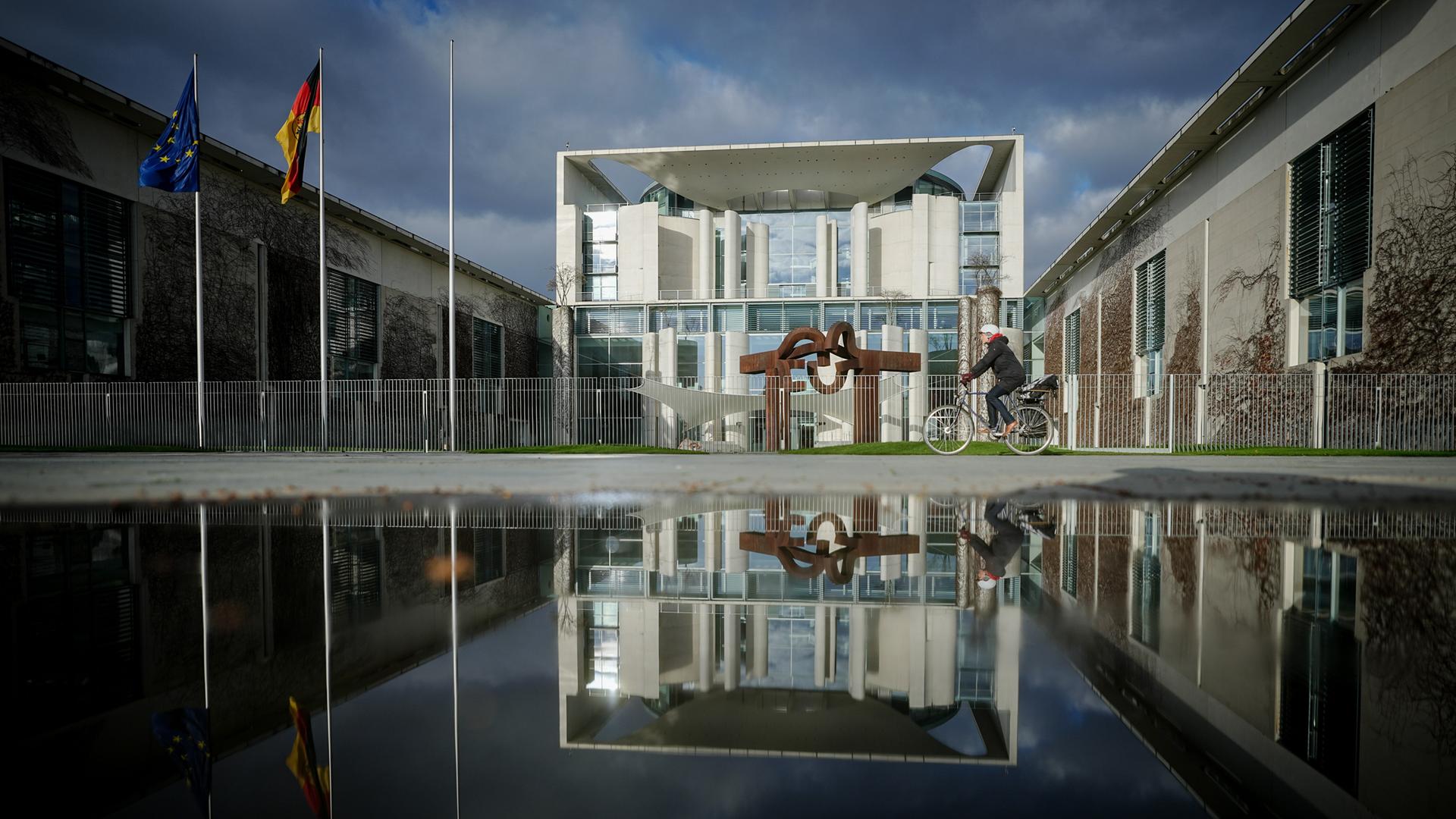 Das Bundeskanzleramt wird von der Sonne angestrahlt, im Hintergrund sind dunkle Wolken. 