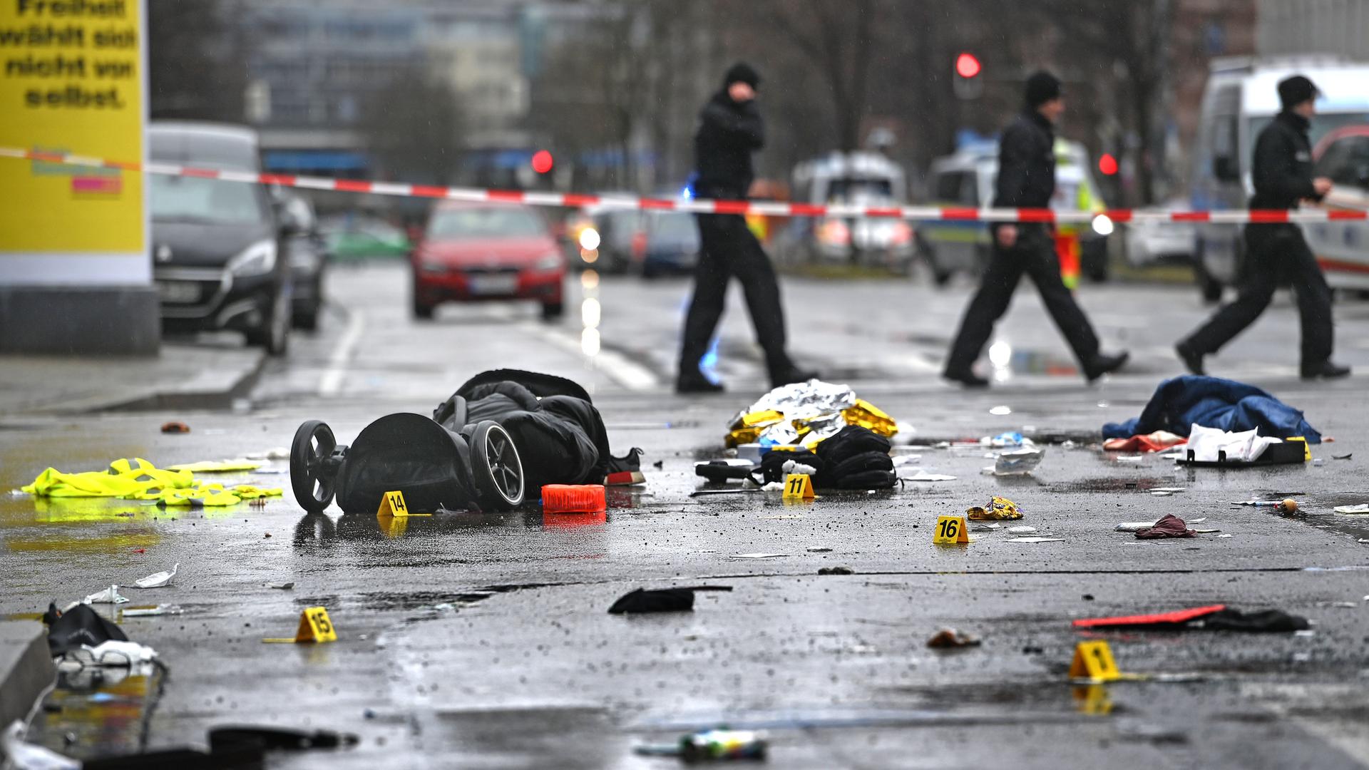 Ein Kinderwagen und weitere  Gegenstände liegen auf der nassen Strasse. Dahinter Polizisten hinter rot-weißem Flatterband.