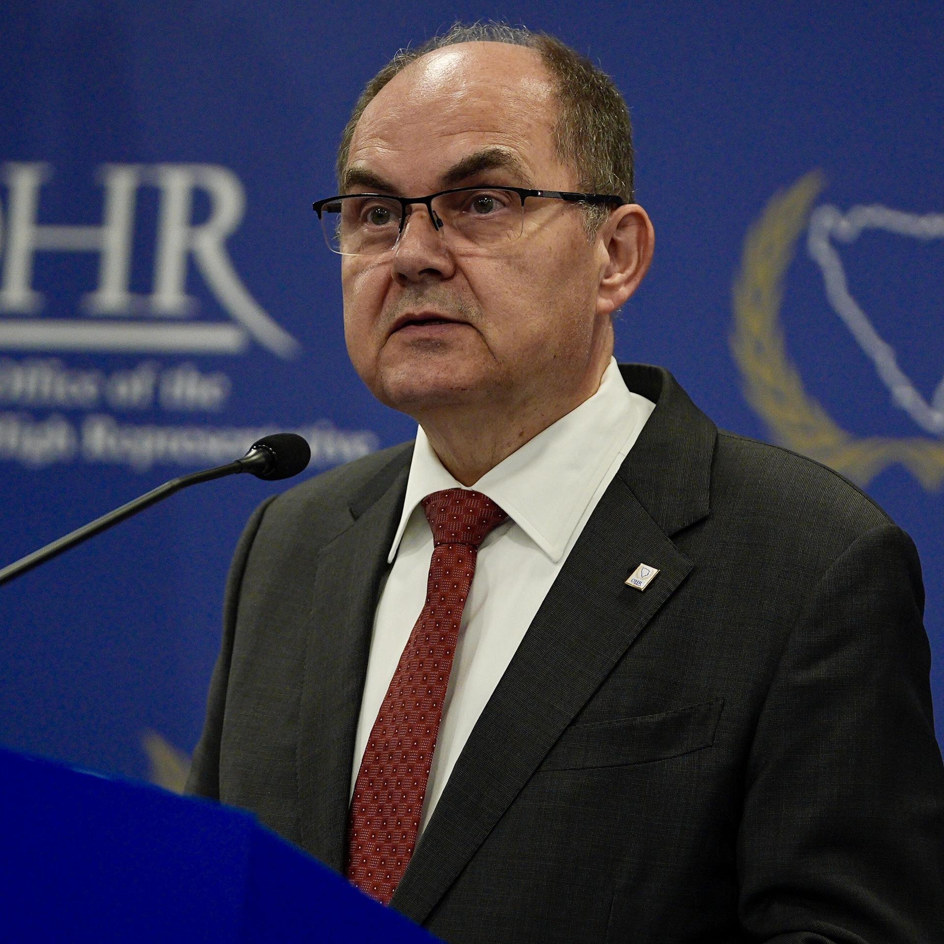 Der CSU-Politiker Christian Schmidt ist Hoher Repräsentant der internationalen Gemeinschaft in Bosnien-Herzegowina. Er steht an einem Redepult, im Hintergrund das Emblem OHR für sein Amt. 