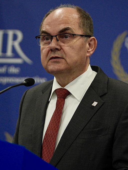 Der CSU-Politiker Christian Schmidt ist Hoher Repräsentant der internationalen Gemeinschaft in Bosnien-Herzegowina. Er steht an einem Redepult, im Hintergrund das Emblem OHR für sein Amt. 