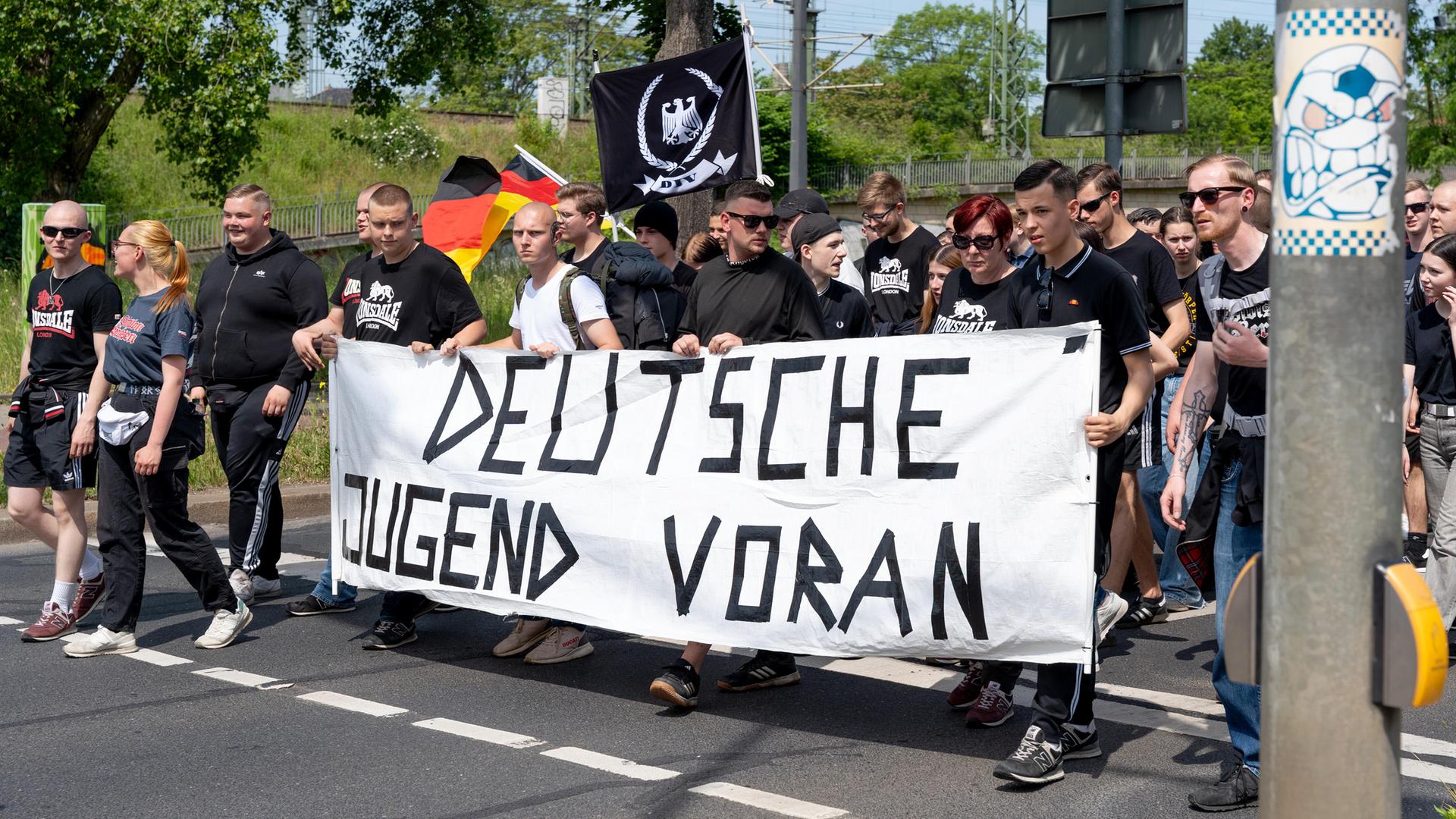 Überwiegend junge Männer mit Deutschlandfahnen und einem Banner mit der Aufschrift "Deutsche Jugend voran" gehen eine Straße entlang: Demo der Jungen Nationalisten.