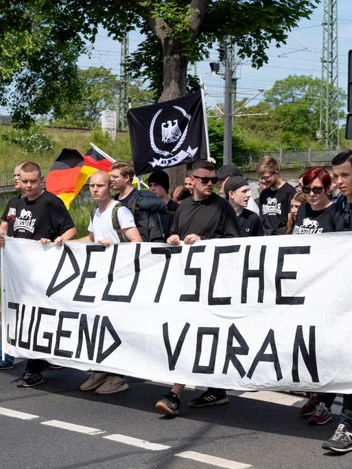 Überwiegend junge Männer mit Deutschlandfahnen und einem Banner mit der Aufschrift "Deutsche Jugend voran" gehen eine Straße entlang: Demo der Jungen Nationalisten.