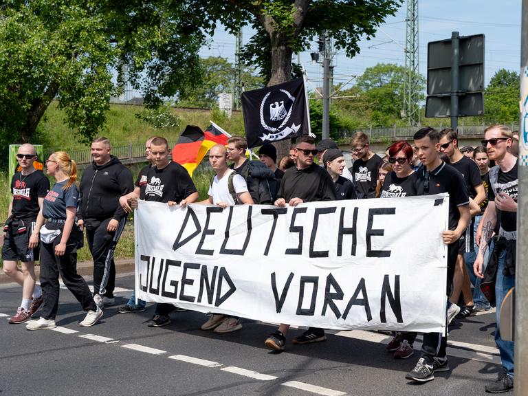 Überwiegend junge Männer mit Deutschlandfahnen und einem Banner mit der Aufschrift "Deutsche Jugend voran" gehen eine Straße entlang: Demo der Jungen Nationalisten.