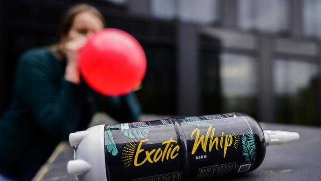 Eine junge Frau konsumiert Lachgas mittels eines Ballons.