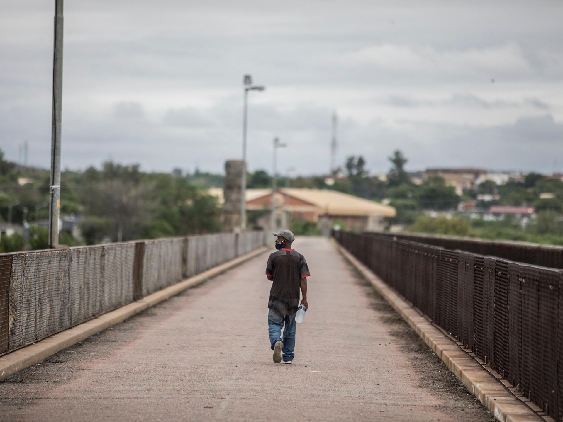 Ein Mann überquert eine leere Brücke.