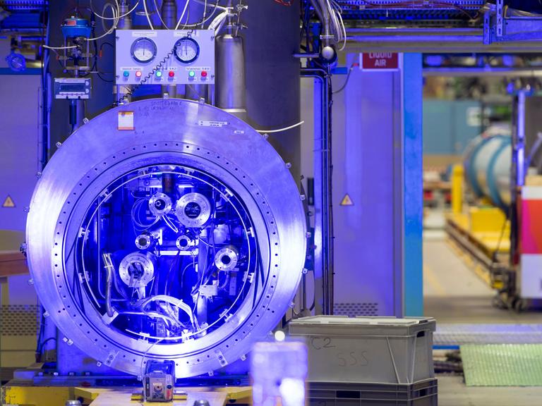 Im Forschungszentrum CERN wird ein kompliziertes technisches Gerät blau ausgeleuchtet.