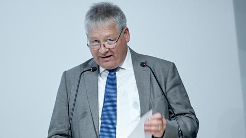 Bruno Kahl, BND-Präsident spricht bei der Eröffnung der Erweiterung des BND-Besucherzentrums. Er steht an einem Rednerpult mit zwei Mikrofonen und hält ein Blatt Papier in der Hand.