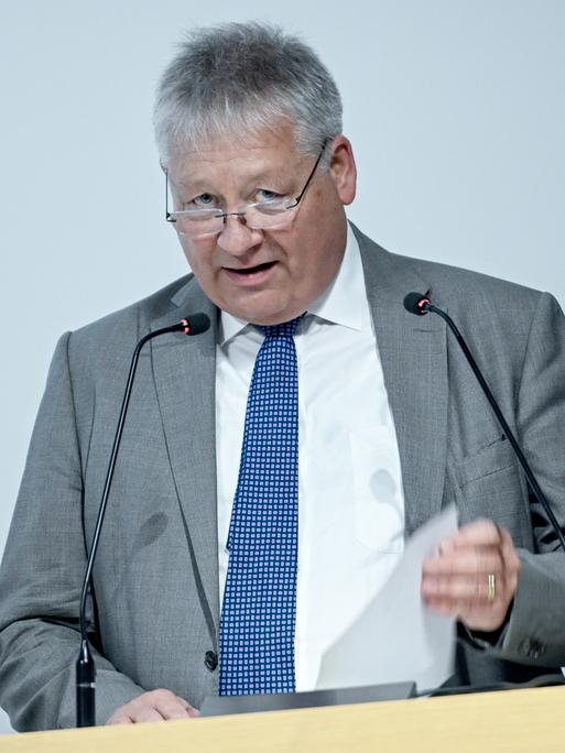 Bruno Kahl, BND-Präsident spricht bei der Eröffnung der Erweiterung des BND-Besucherzentrums. Er steht an einem Rednerpult mit zwei Mikrofonen und hält ein Blatt Papier in der Hand.