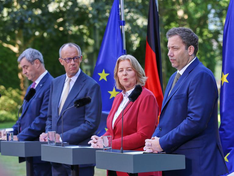 Bayerns Ministerpräsident Markus Söder (CSU), Bundeskanzler Friedrich Merz (CDU), Bundesministerin für Arbeit und Soziales Bärbel Bas (SPD), Bundesminister der Finanzen Lars Klingbeil (SPD) stehen nebeneinander vor Mikrofonen im Freien Bayerns Ministerpräsident Markus Söder (CSU), Bundeskanzler Friedrich Merz (CDU), Bundesministerin für Arbeit und Soziales Bärbel Bas (SPD), Bundesminister der Finanzen Lars Klingbeil (SPD) stehen nebeneinander vor Mikrofonen im Freien
