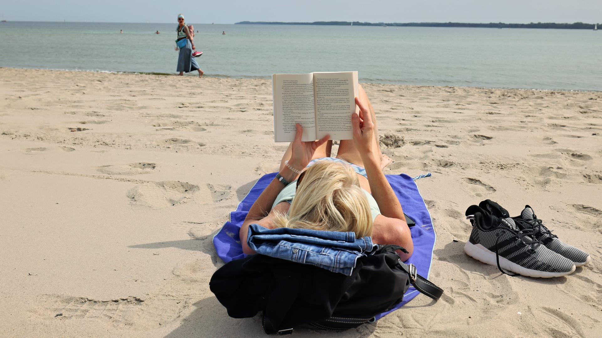 Eine Urlauberin liest an einem Badestrand an der Ostsee ein Buch. Eine Urlauberin liest an einem Badestrand an der Ostsee ein Buch.