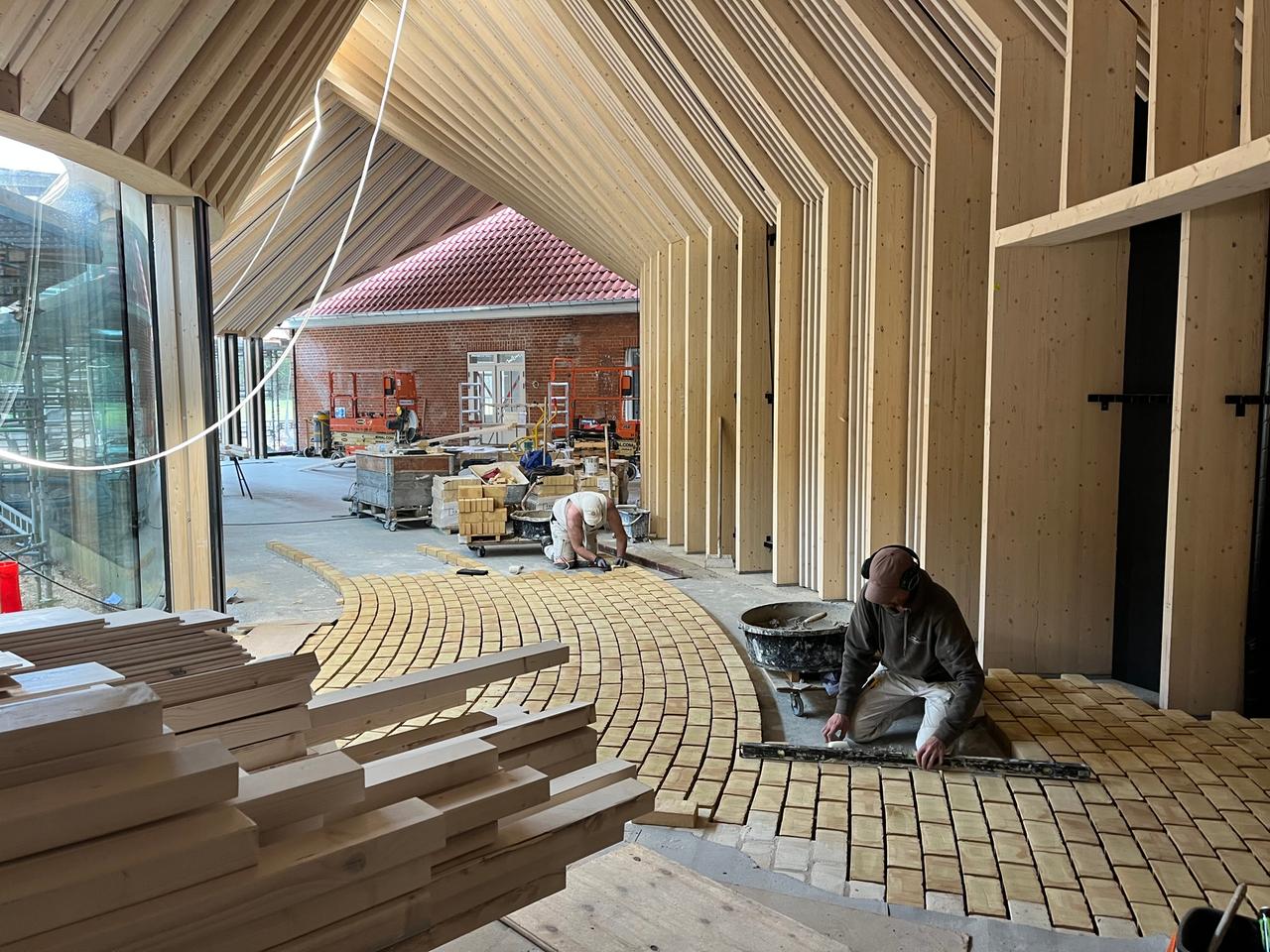 Bauarbeiter legen den Boden in einem verglasten Flur des neuen Fluchtmuseums in Oksbøl.