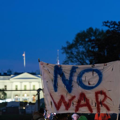 Aktivisten halten ein Transparent mit den Worten "No War" in die Höhe, im Hintergrund ist das Weiße Haus zu sehen