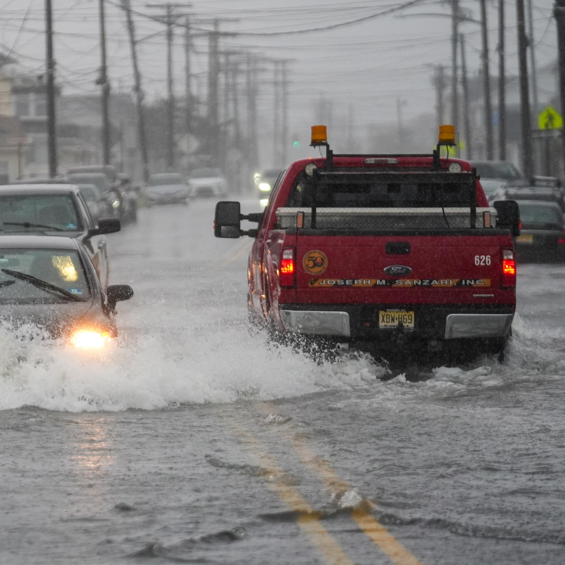 Das Foto zeigt Autos, die in Point Pleasant/New Jersey durch eine überflutete Straße fahren.