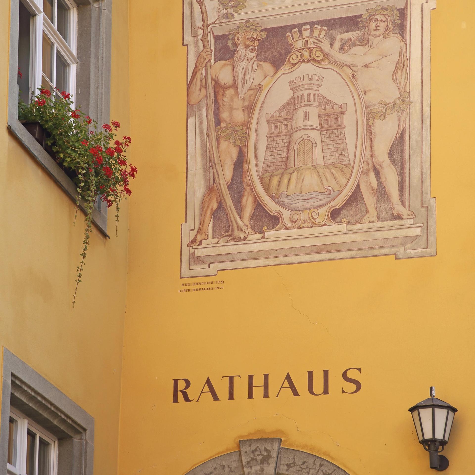 Historische Wandmalerei mit Stadtwappen, darunter die Inschrift "Rathaus" auf dunkelgelbem Verputz