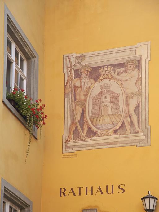 Historische Wandmalerei mit Stadtwappen, darunter die Inschrift "Rathaus" auf dunkelgelbem Verputz