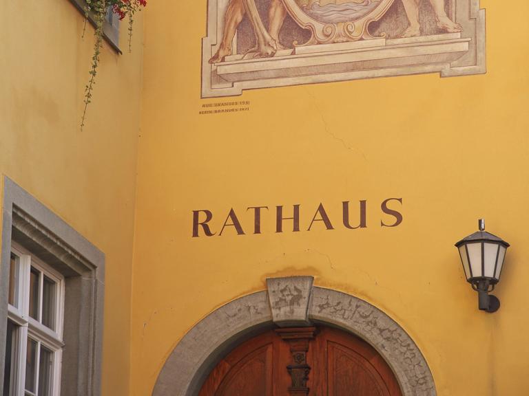 Historische Wandmalerei mit Stadtwappen, darunter die Inschrift "Rathaus" auf dunkelgelbem Verputz
