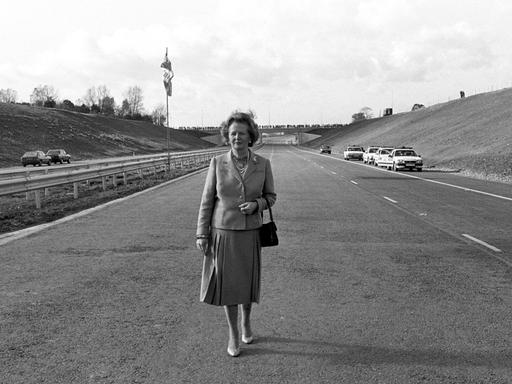 Ein Scharz-Weiß-Foto zeigt die damalige britische Premierministerin Margaret Thatcher nach der offiziellen Eröffnung der Autobahn M25 in Hertfordshire allein auf der Fahrbahn stehend.