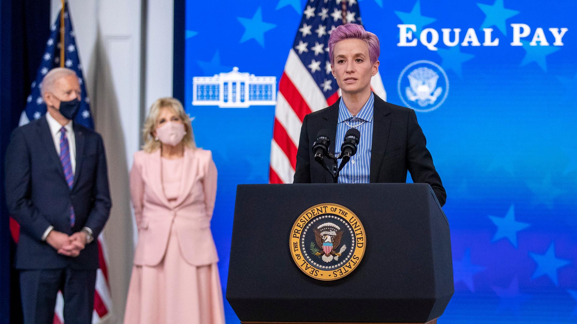 US-Fußballerin Megan Rapinoe am Rednerpult vor US-Präsident Joe Biden und First Lady Jill Biden, im Hintergrund steht "Equal pay day"