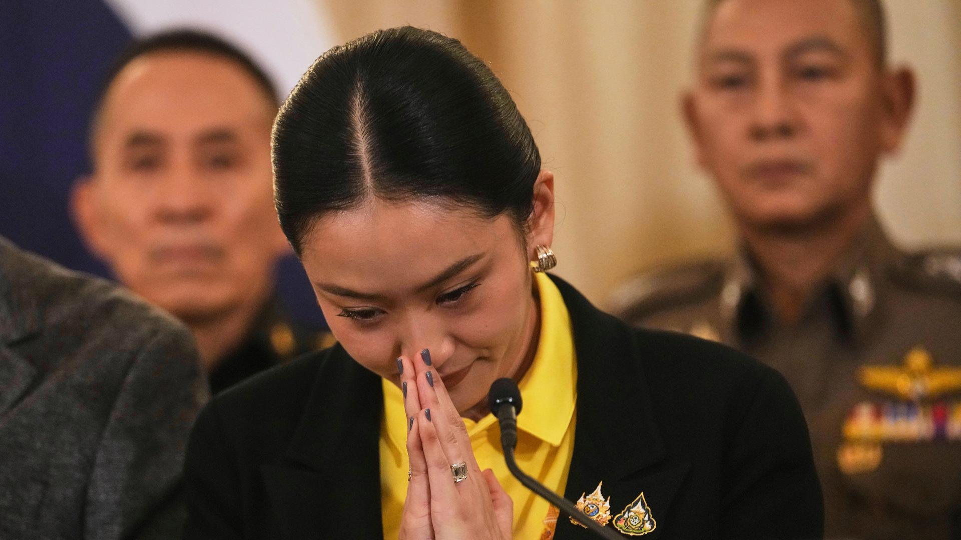 Thailands Ministerpräsidentin Paetongtarn Shinawatra bereitet sich darauf vor, das Regierungsgebäude in Bangkok zu verlassen. Sie hat die Hände vor ihrem Gesicht gefaltet. 