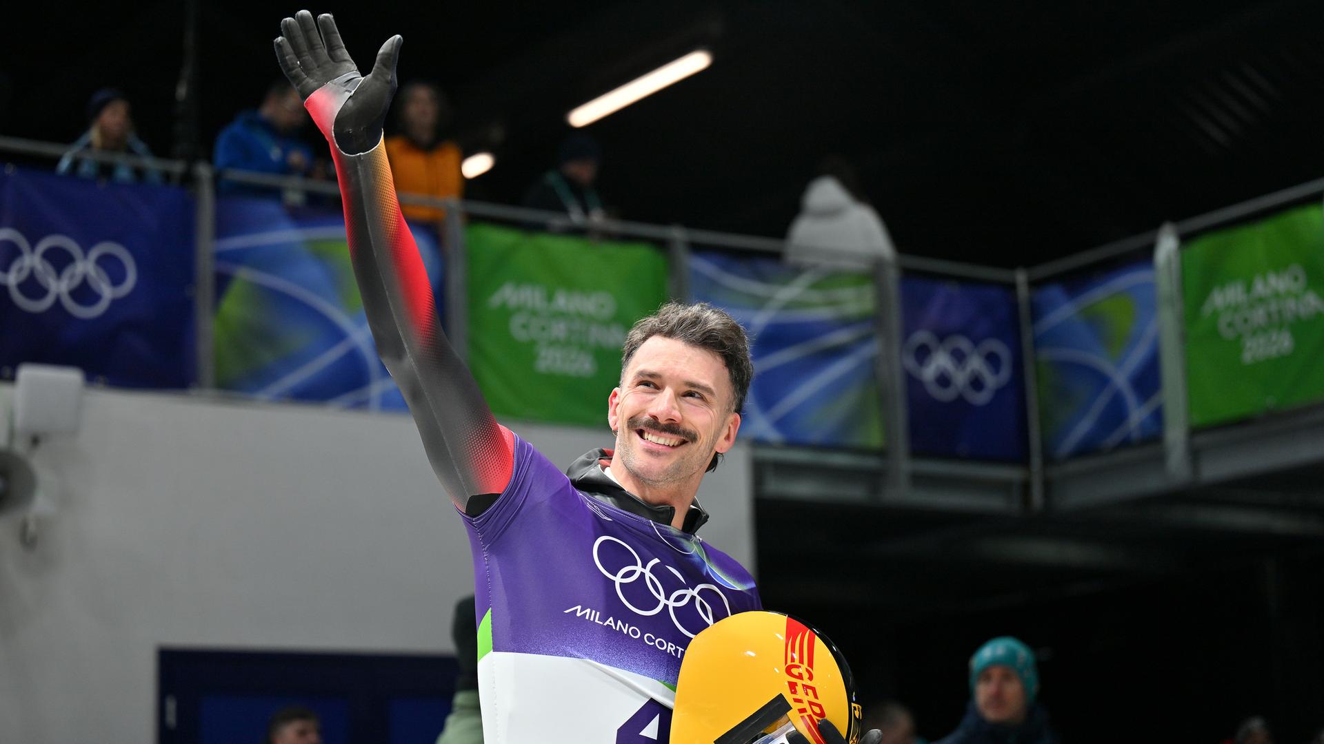 Axel Jungk reckt eine Hand zum Jubel hoch, in der anderen hält er seinen Skeleton.Schutzhelm. Axel Jungk reckt eine Hand zum Jubel hoch, in der anderen hält er seinen Skeleton.Schutzhelm.