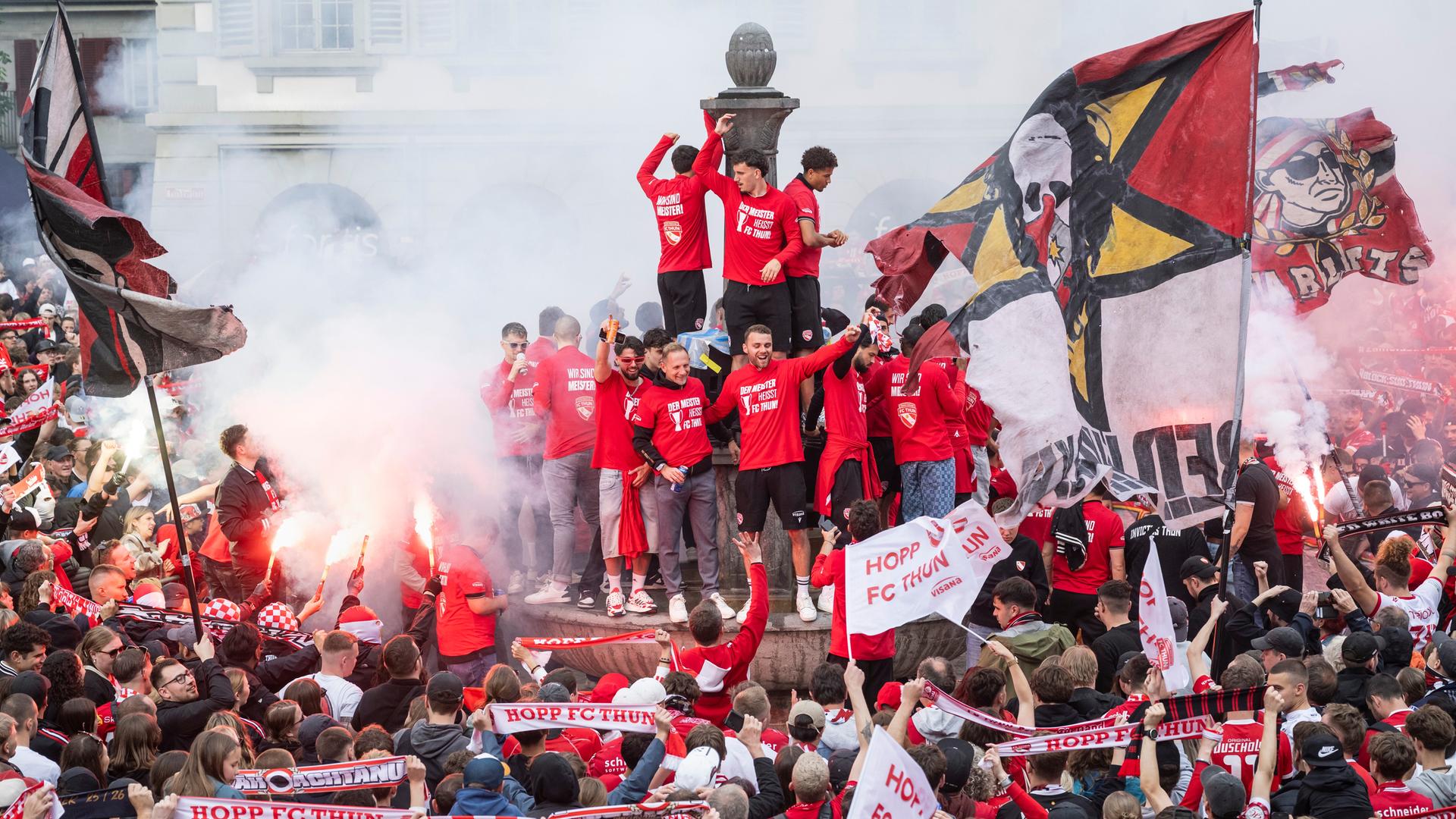 Fans des FC Thun feiern zusammen mit der Mannschaft, die auf einem Brunnen steht, die Schweizer Fußball-Meisterschaft. 