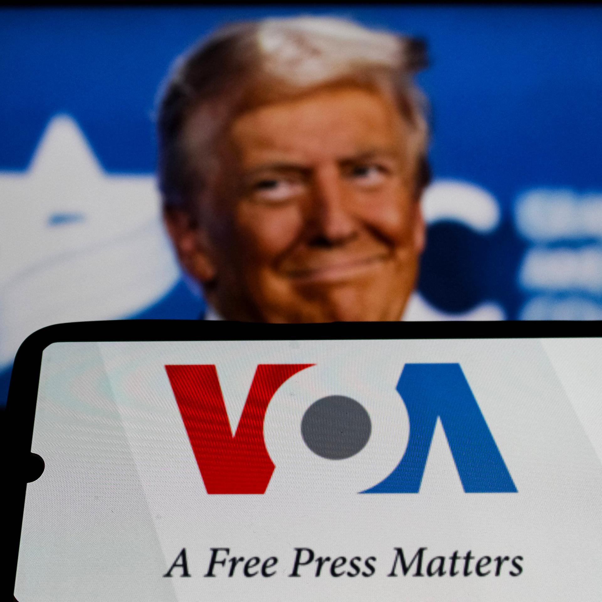 Ein Bildcollage zeigt im Vordergrund das Logo des US-Auslandssenders Voice of America. Dahinter der Kopf von Donald Trump.
