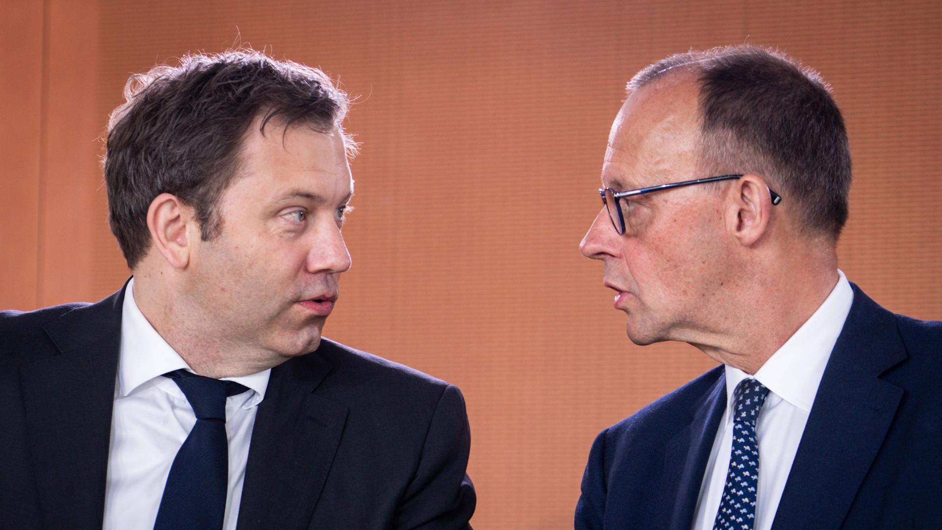 Bundeskanzler Friedrich Merz blickt zu Lars Klingbeil, Bundesminister der Finanzen. Sie sind im Gespräch. Sie sind im Profil zu sehen.
