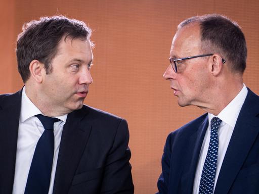 Bundeskanzler Friedrich Merz blickt zu Lars Klingbeil, Bundesminister der Finanzen. Sie sind im Gespräch. Sie sind im Profil zu sehen.