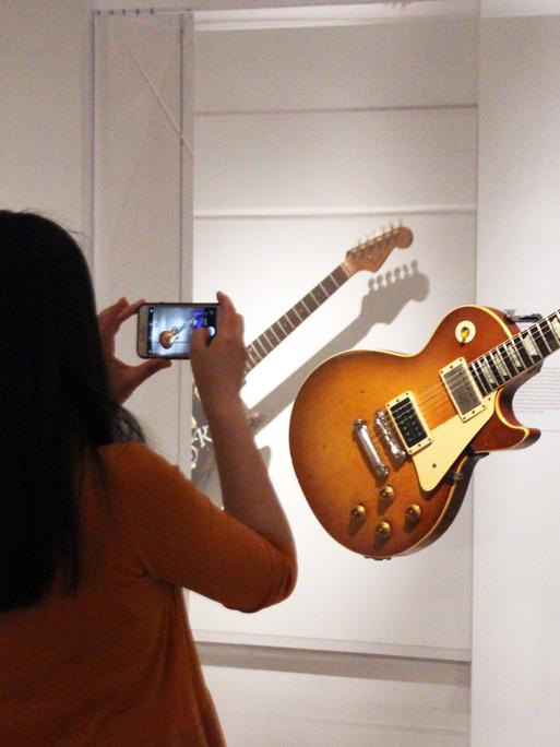 Eine Besucherin des Metropolitan Museum in New York fotografiert die ausgestellte Gibson-Gitarre von Jimmy Page.