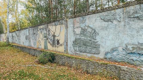 Wandrelief an einer Außenmauer zeigt einen Schützenpanzer.