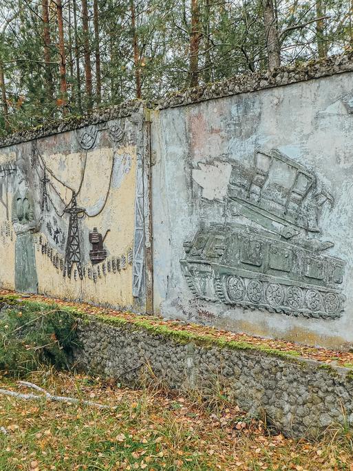 Wandrelief an einer Außenmauer zeigt einen Schützenpanzer.