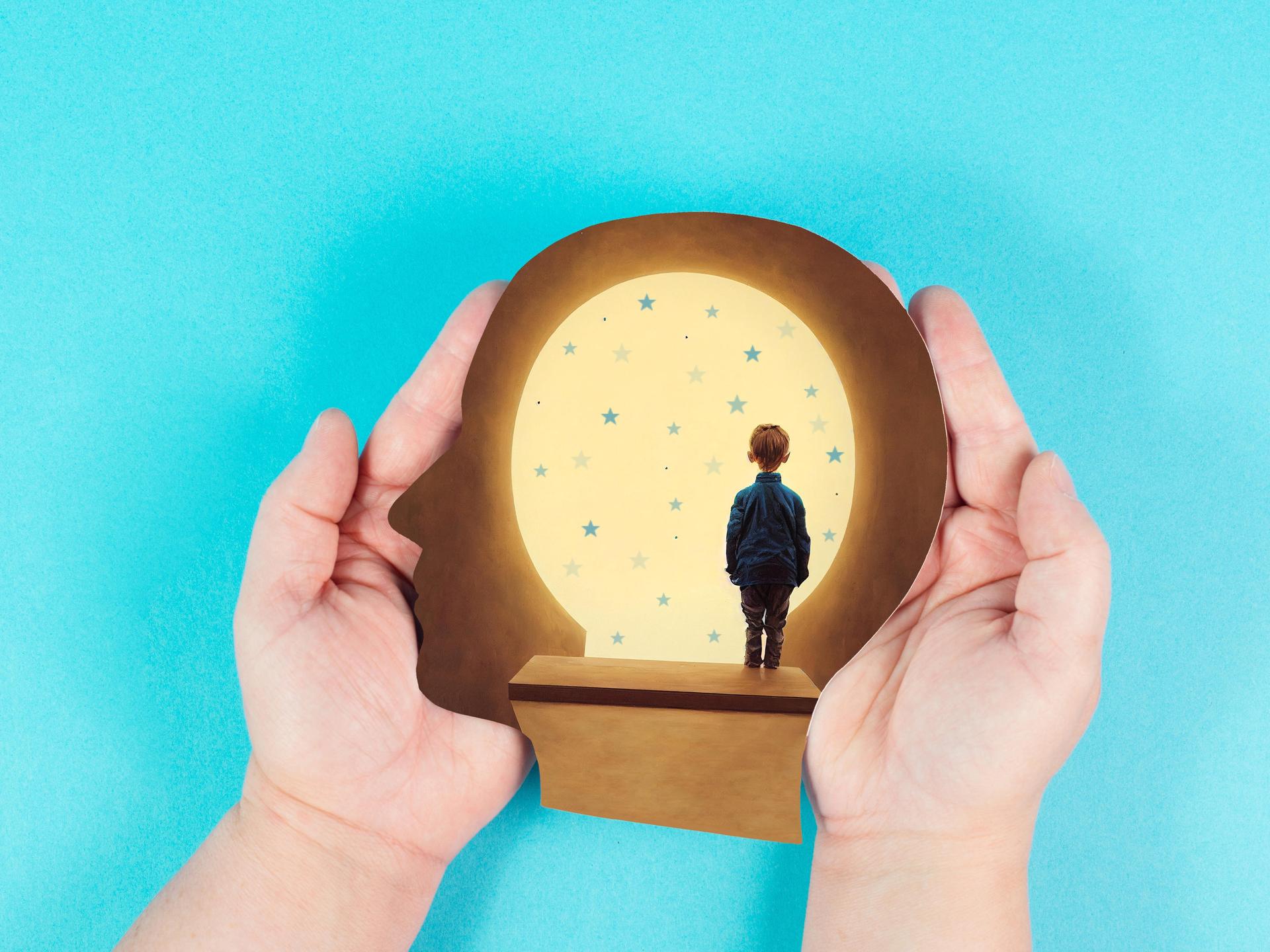 Die Illustration zeigt zwei Hände, die ein Umriss eines Kopfes halten. Darin steht ein Kind und blickt in die Ferne. 