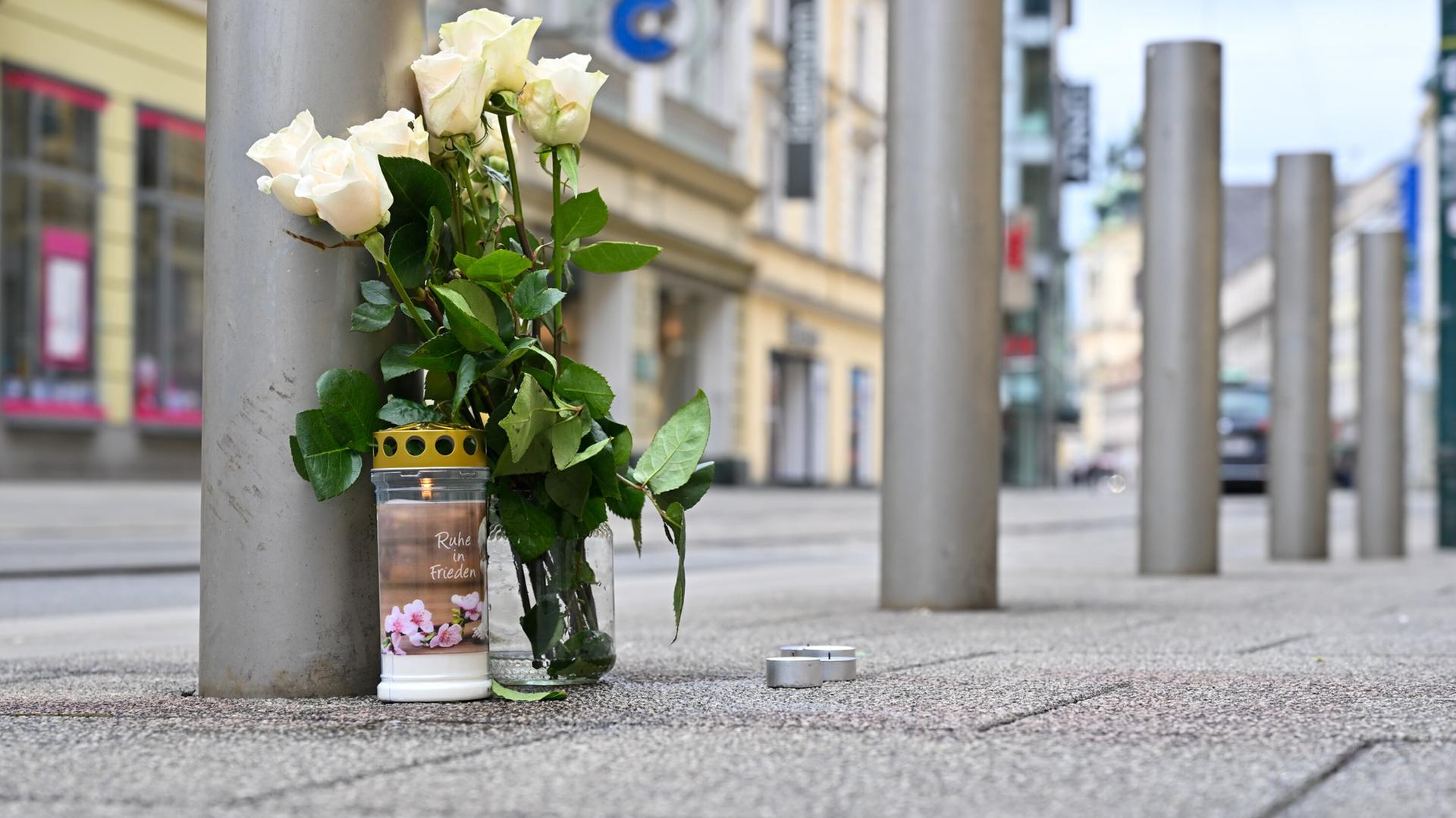 Blumen und eine Kerze stehen in der Nähe des Tatorts nach einem tödlichen Messerangriff in der Linzer Innenstadt.
