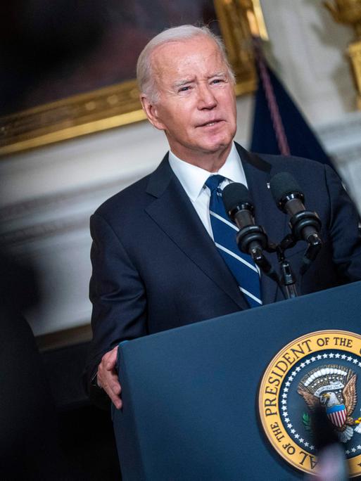 Ein Mann in dunklem Anzug steht an einem Rednerpult, es ist der US-Präsident Joe Biden. Er spricht vor Journalisten.